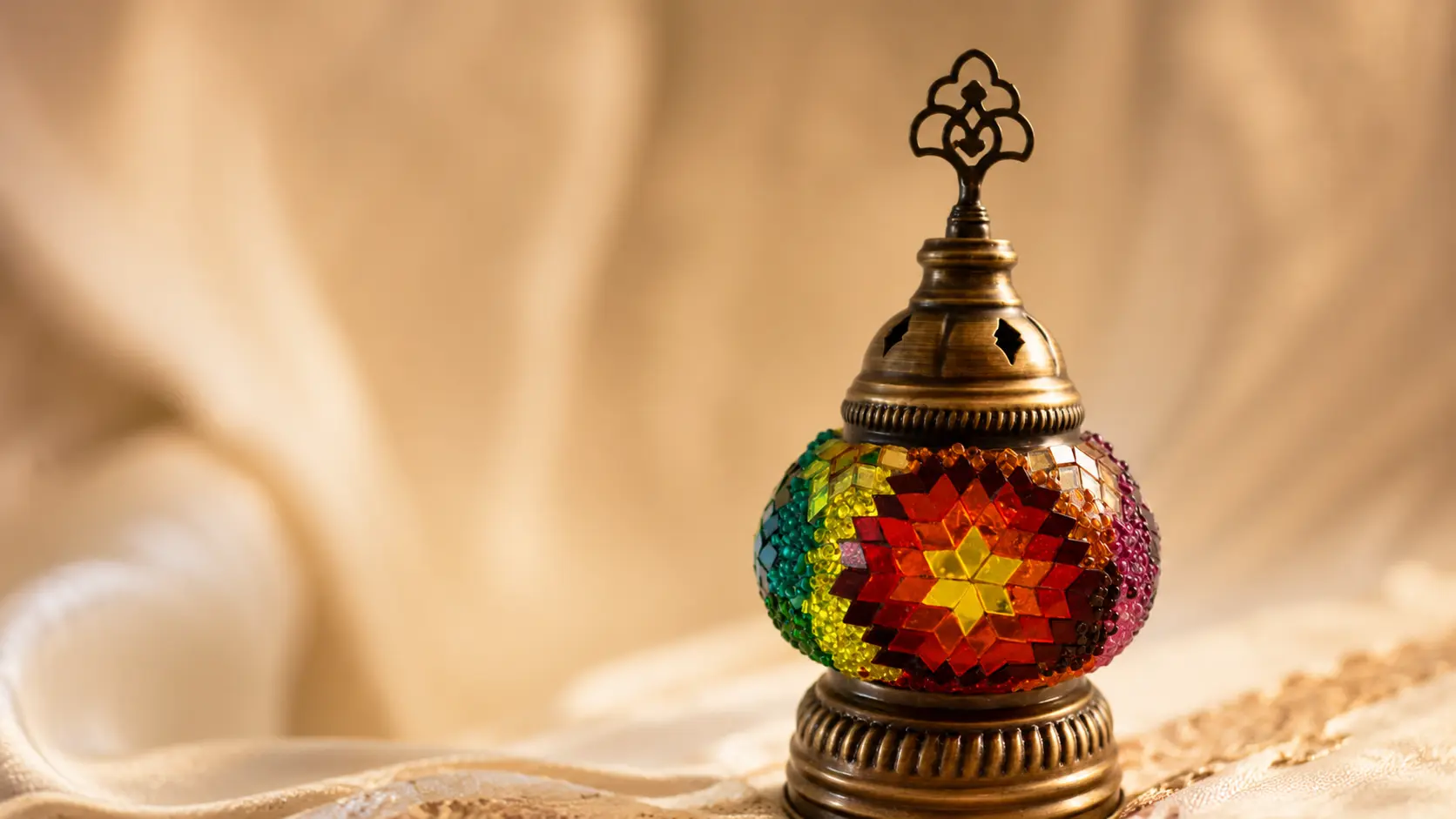 Macro shot of a handmade oriental mosaic lamp with glass tiles, beads, and brass ornaments at Orient Art Studio Berlin